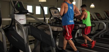 Two men running on treadmills in a modern gym, promoting fitness and health.